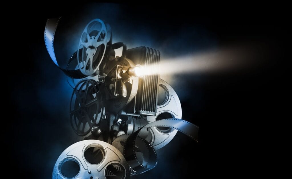 A film projector surrounded by reels of film.