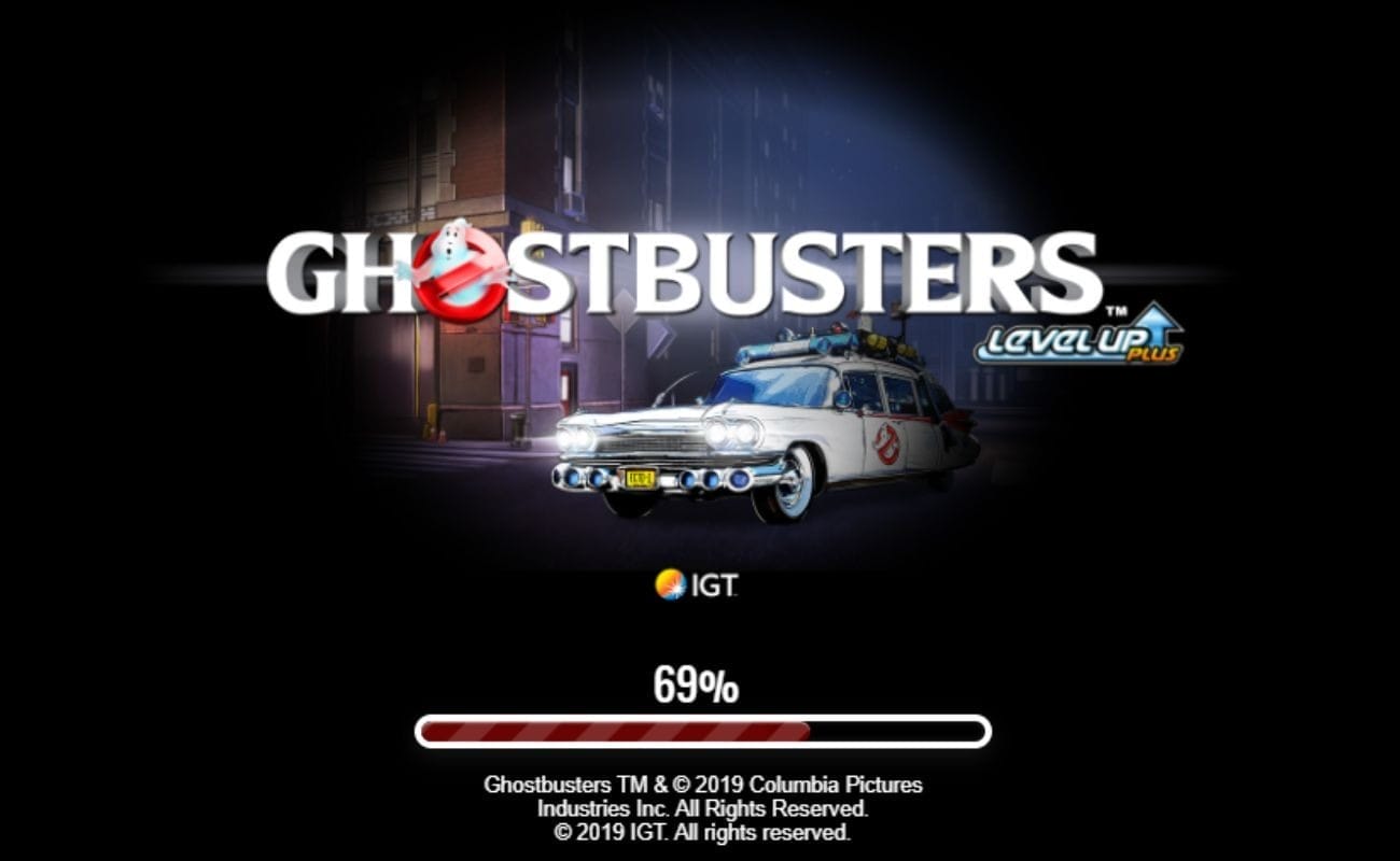 A screenshot of the Ghostbusters Plus loading screen showing the game’s logo and the Ectomobile lit up by a spotlight on a black background. 