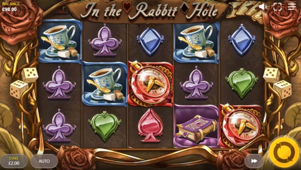 In the Rabbit Hole reels with dice and roses set as the reel frame against a brown-hued background. The reels are filled with playing card suits such as blue diamonds, green hearts, red spades and purple clubs alongside the Free Spins symbol, a teacup and a book.