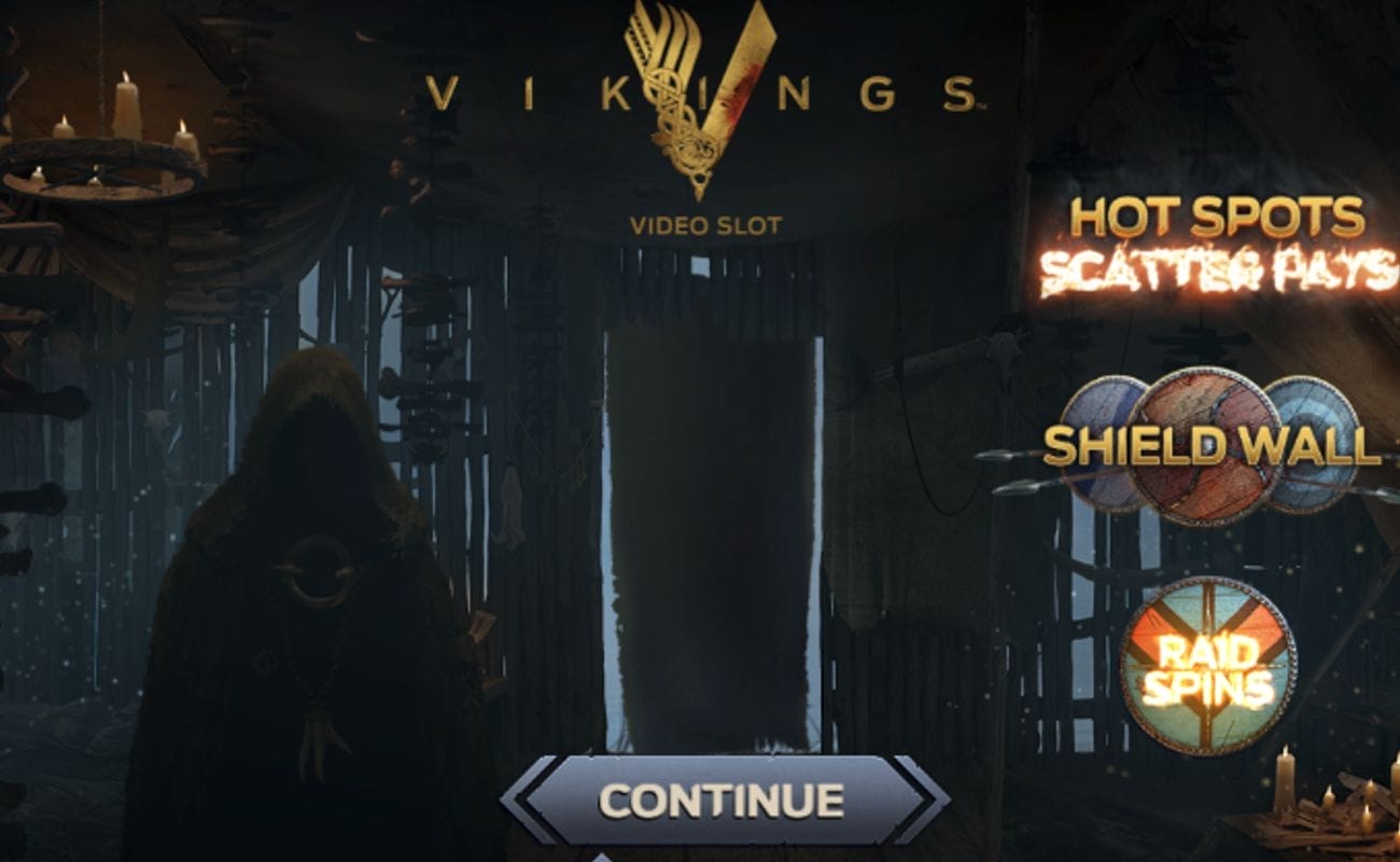 The Vikings online slot loading screen, displaying a dark, cloaked figure in a wooden house with the Vikings series logo and three feature names lit up.