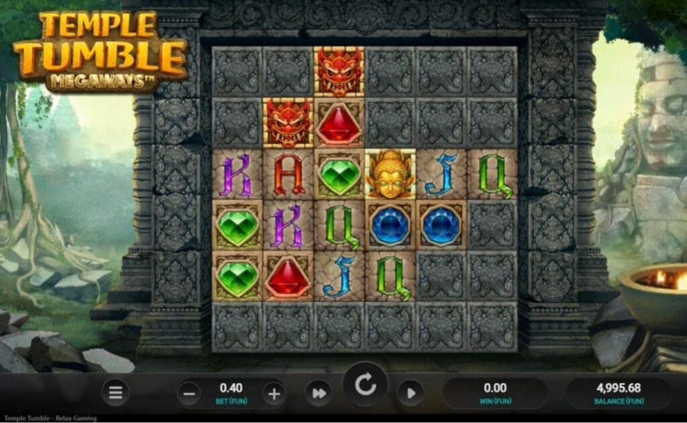 A screenshot of Temple Tumble Megaways. The game is set in the ruins of a jungle temple against a wall filled with symbols, including gems, rubies, and opals, as well as deities and demons.