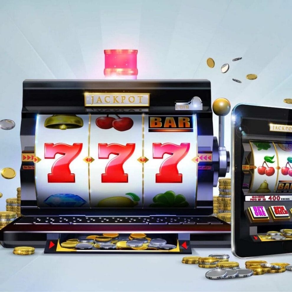 An online slot concept image showing a classic slot game that has been merged with a laptop and a digital tablet, with gold and silver coins surrounding the devices.