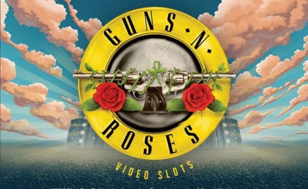 Guns n’ Roses online slot logo in yellow, black, and silver. There are guns and red roses on the logo emblem. The background show white cartoonish clouds and a blue sky over a massive concert with thousands of people.