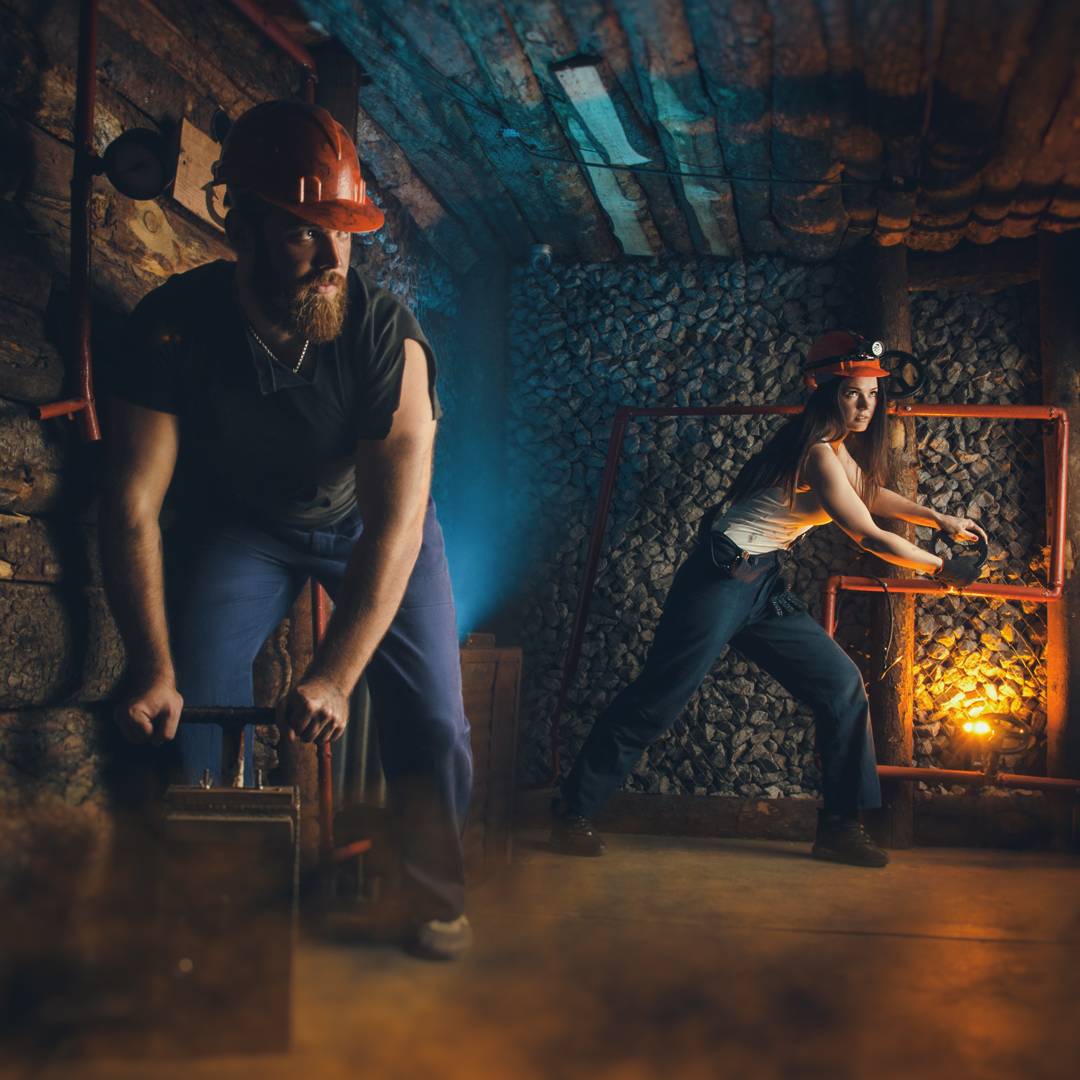 Two miners in orange hardhats working in a mine.