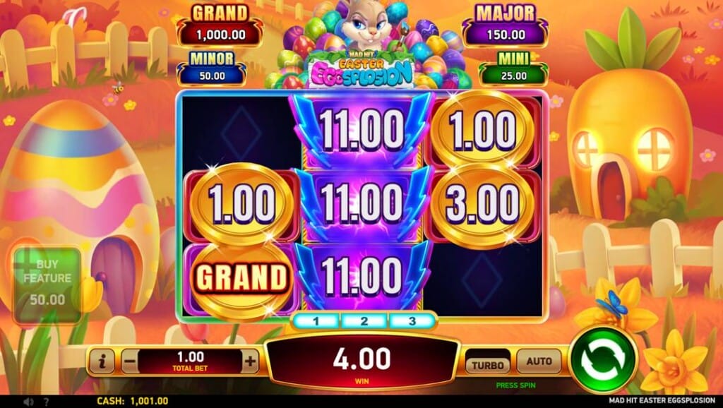 A screenshot of the bonus feature in Mad Hit Easter Eggsplosion. A cartoon village with egg and carrot houses is bathed in a golden light. In the foreground are the slot reels filled with Mad Hit symbols and gold coins with cash and jackpot prizes.