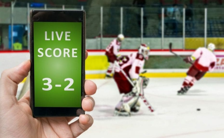 Live score online betting on a mobile phone app with ice hockey players blurred in the background