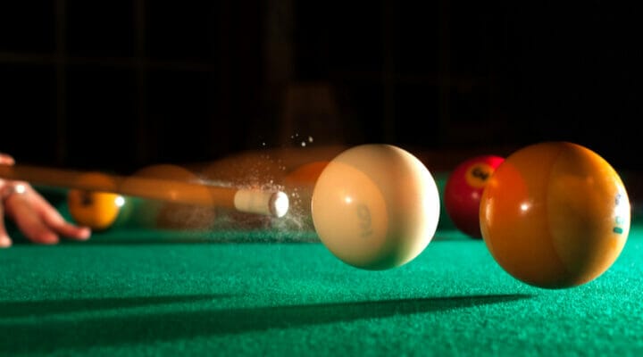 A player hits the white ball with the cue stick.
