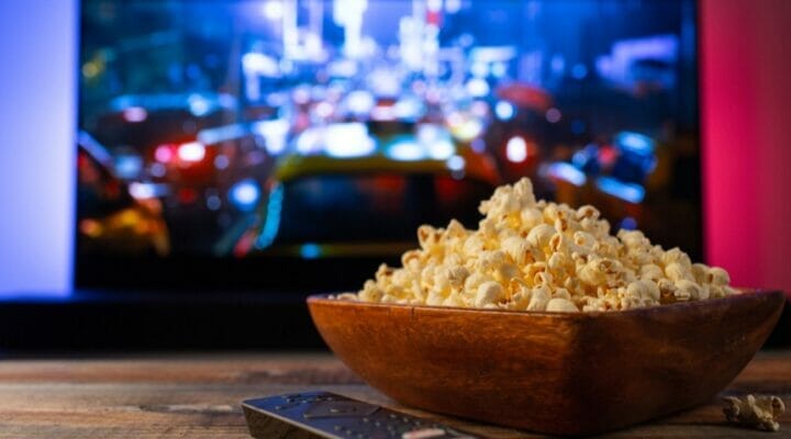 A bowl of popcorn sits on a table in front of a TV.