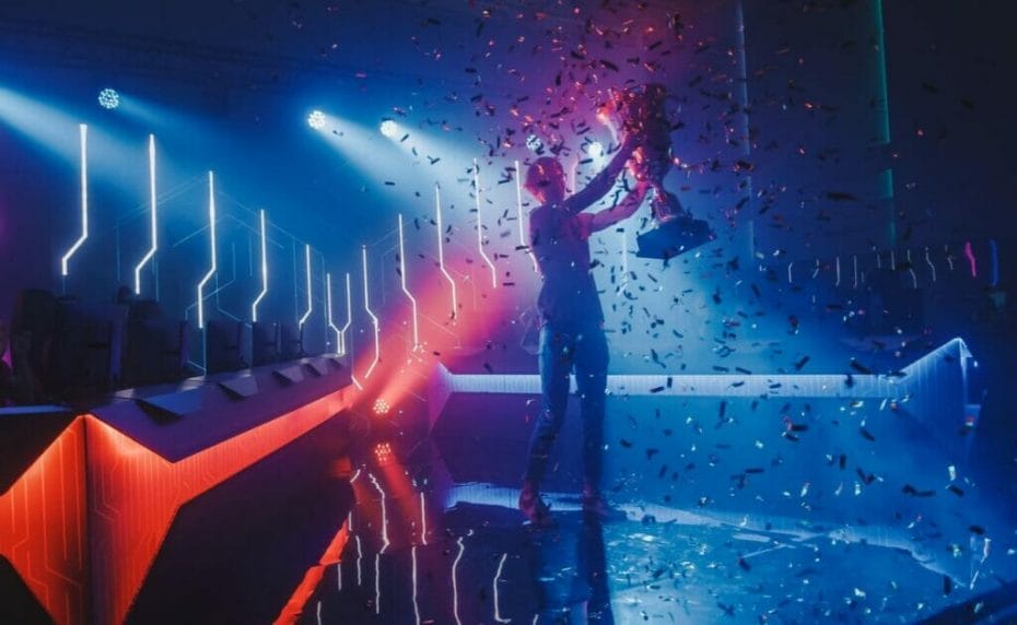 Ilustrasi seorang pemenang eSports berdiri di atas panggung neon, memegang piala sambil dikelilingi konfeti.