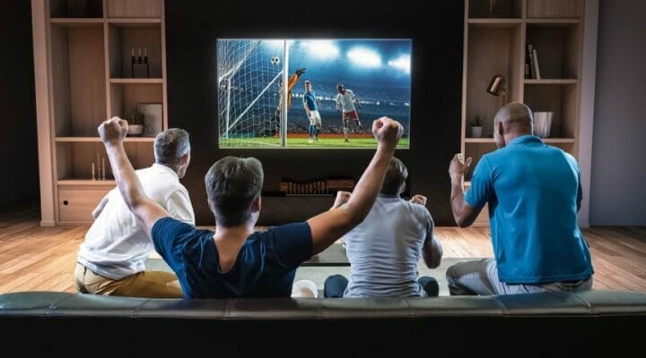 A group of friends watching a soccer match on TV in the living room.