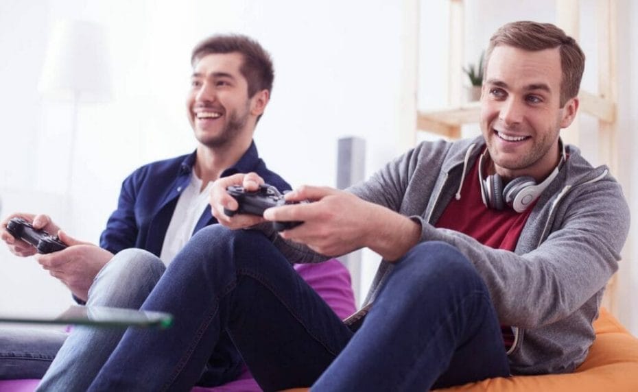 Two men sit on bean bags playing video games.
