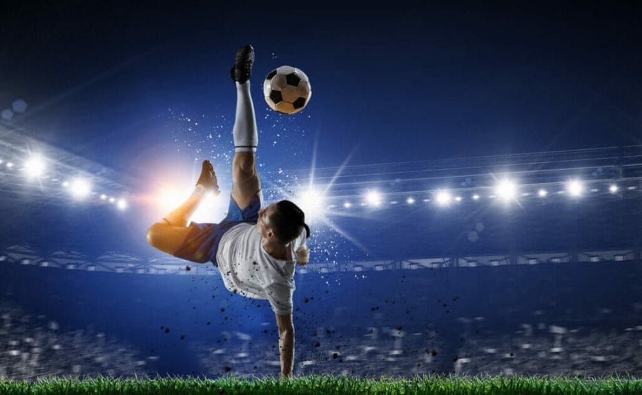A soccer player does an overhead kick with lights and a stadium in the background.