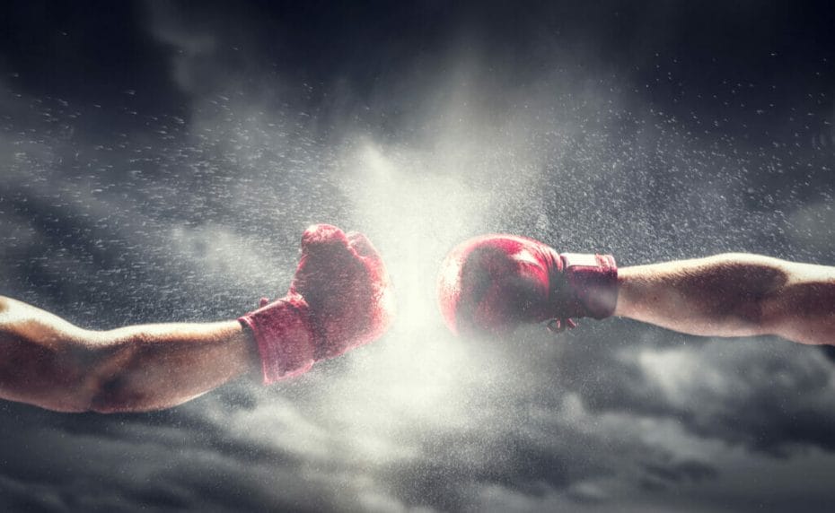 Two arms with boxing gloves coming together with water spattering and a gray background.