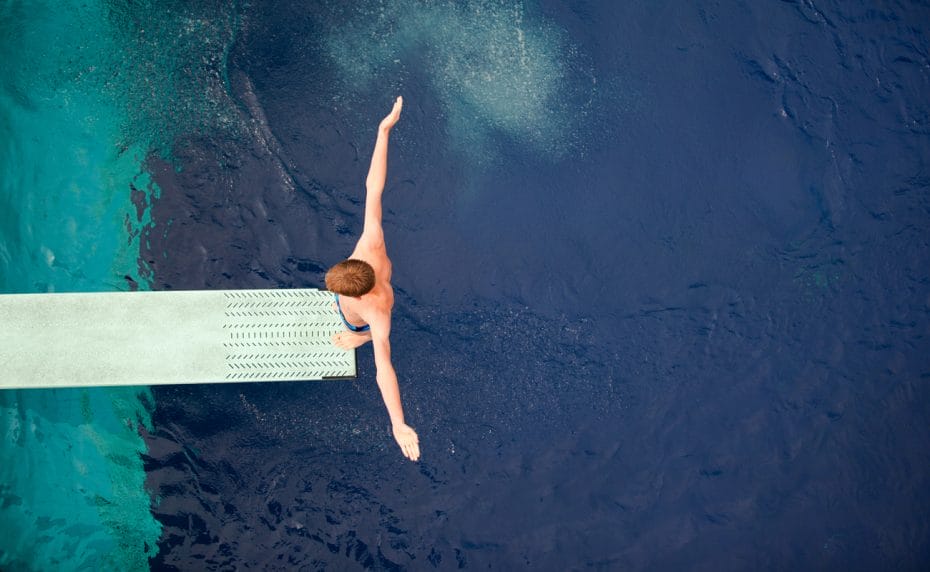 Top view of a diver on a board with his arms out preparing to dive into a pool.