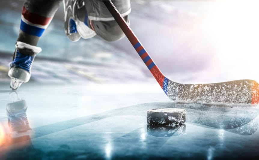 Ice hockey player on the ice coming in to hit the puck with their stick.