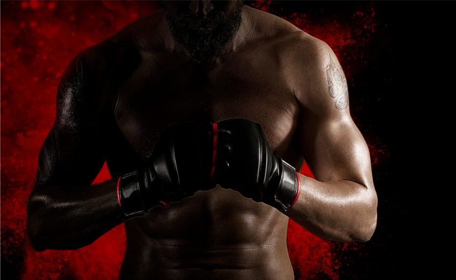An MMA fighter stands with his hands together in front of a red and black background.