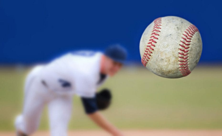     Bola bisbol dalam fokus dengan pelempar tidak fokus di latar belakang.