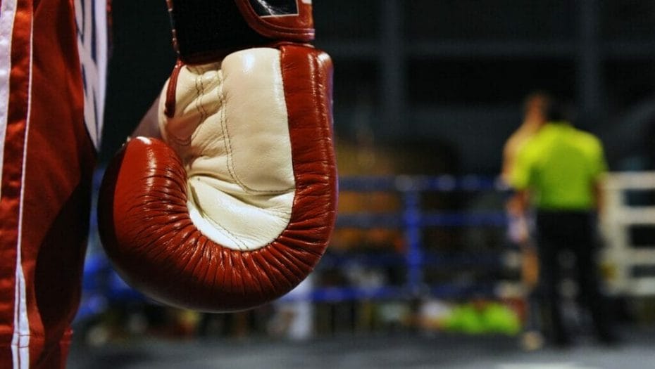 A close-up of a boxer’s glove while he stands waiting between rounds.