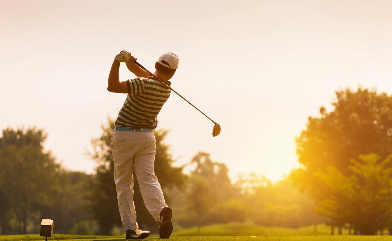  A golfer tees off into the sunrise.