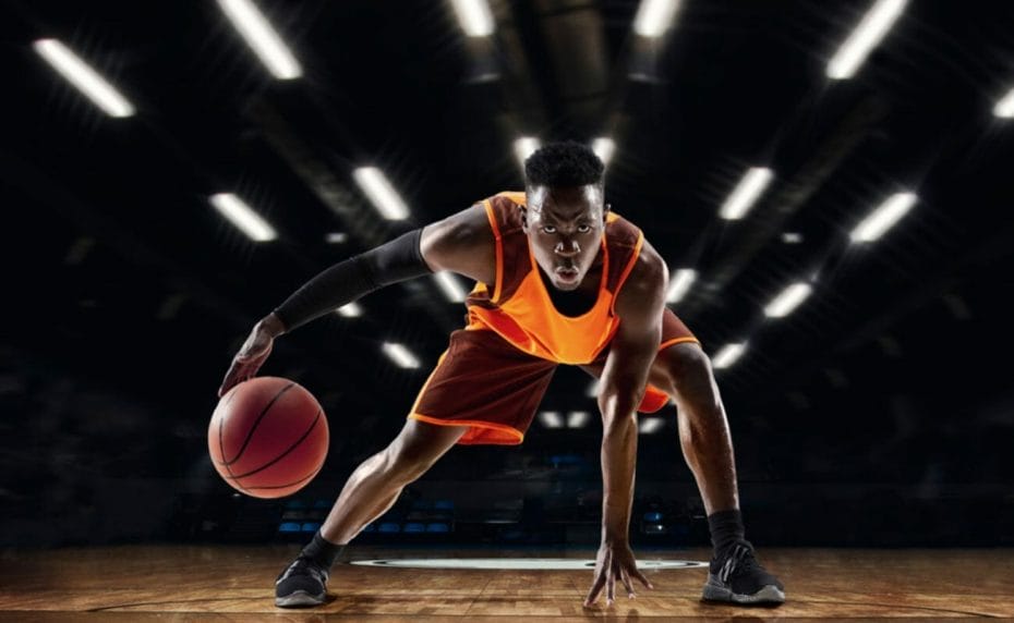  A basketball player looks into the camera while dribbling.