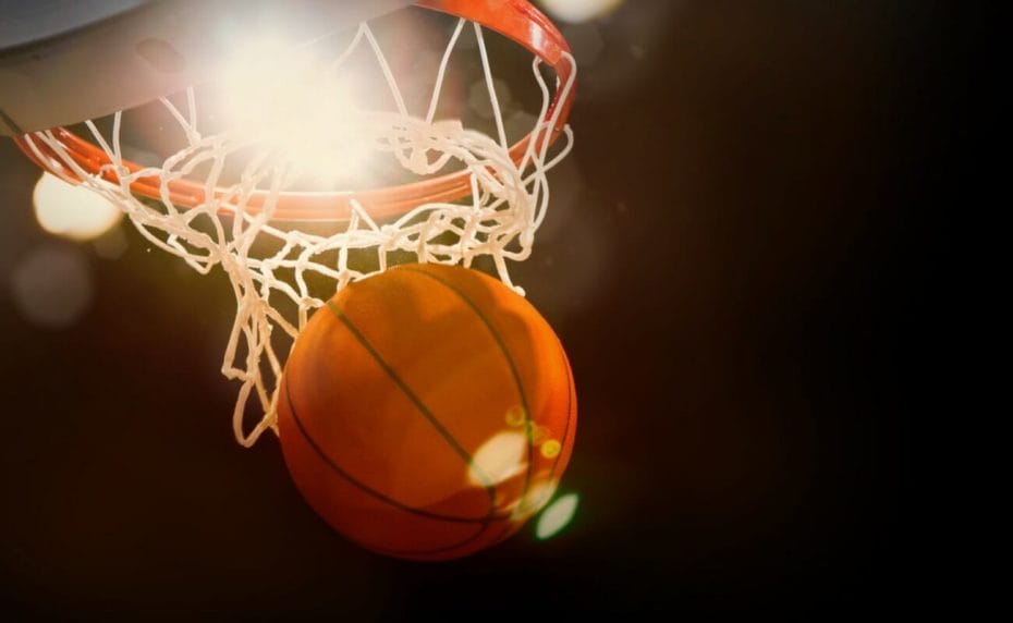  A basketball goes through a hoop with a bright light behind it.