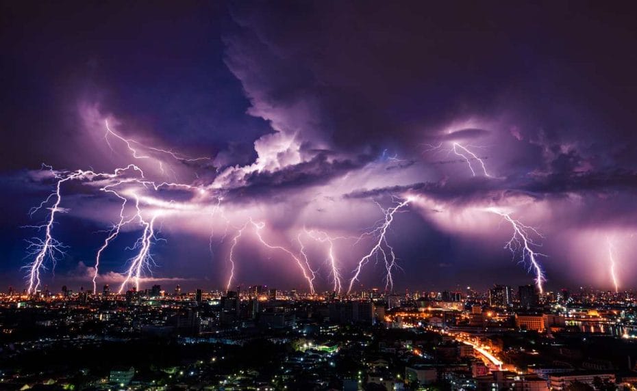 Lightning storm over a city in purple light.