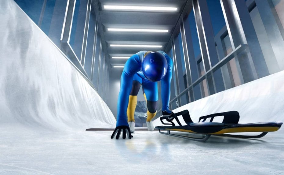 An athlete in a blue lycra suit descends on an ice track with a luge.