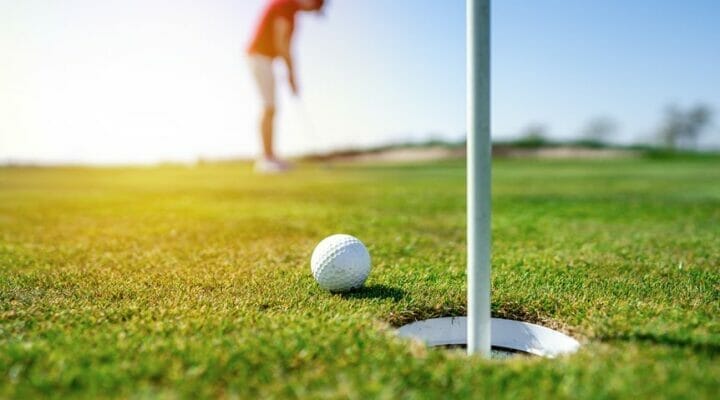 Close-up of a golf ball next to the hole and flag.