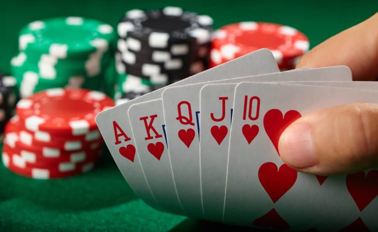 poker player showing a royal flush with casino chips in the background