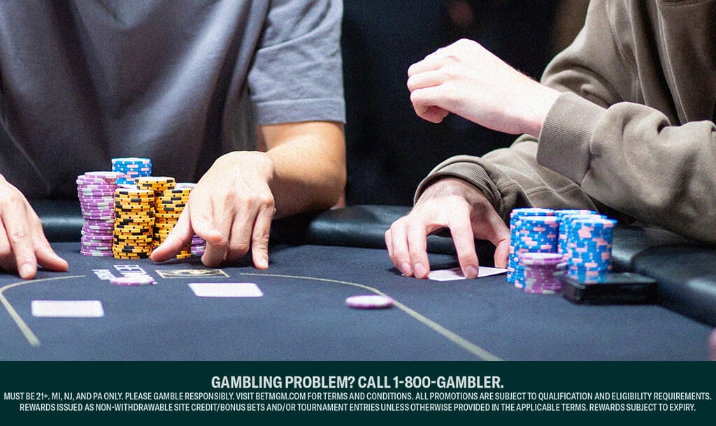 Close-up of two poker players’ arms and hands at a casino table, focused on the game, with stacks of colorful chips in front of them. The table features playing cards and poker chips