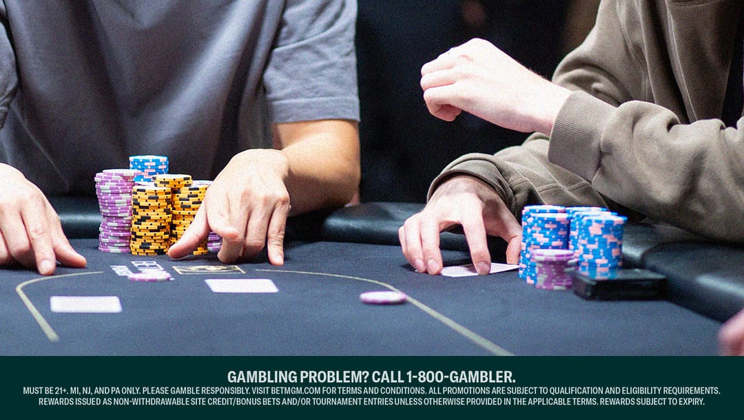 Close-up of two poker players’ arms and hands at a casino table, focused on the game, with stacks of colorful chips in front of them. The table features playing cards and poker chips