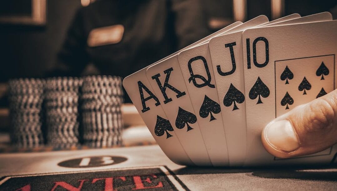 Close-up of a royal flush in playing cards during a poker game with casino chips in the background.