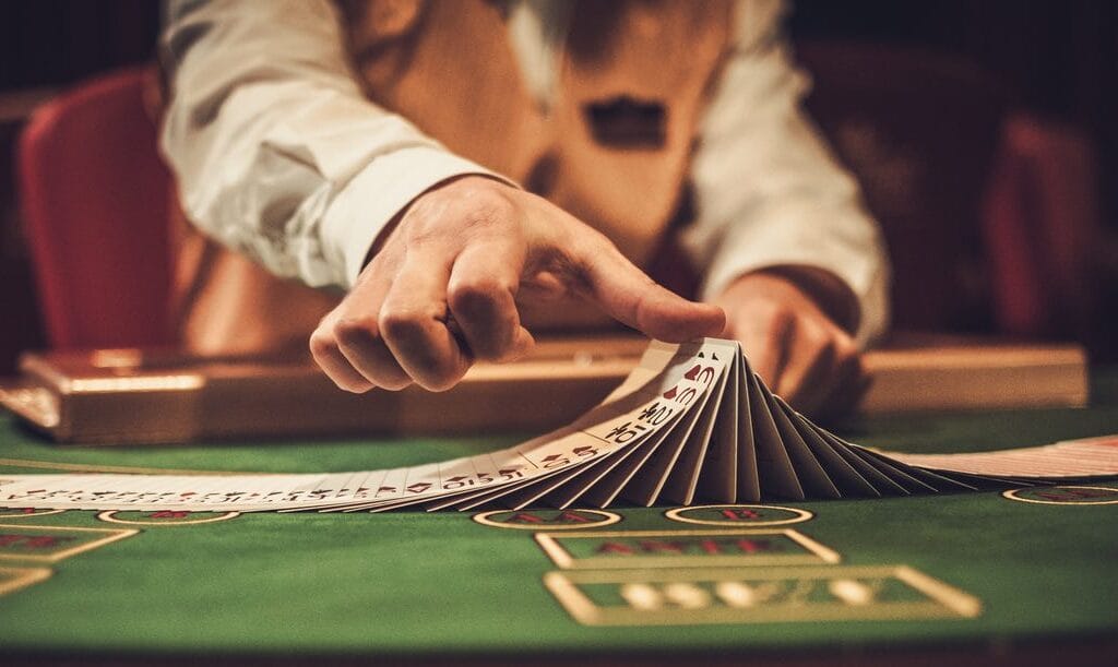 A croupier spreading playing cards at a gambling table in a casino.