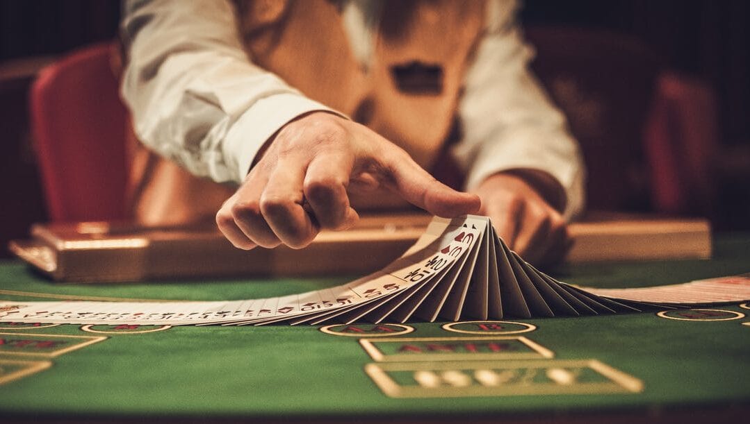 A croupier spreading playing cards at a gambling table in a casino.
