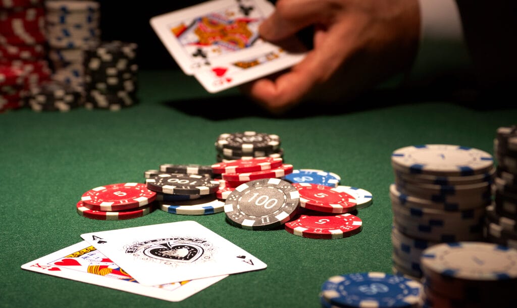 A King and an Ace on a table with chips and a player’s hand with cards in the background