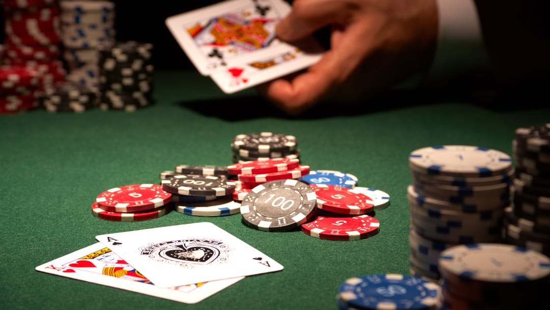 A King and an Ace on a table with chips and a player’s hand with cards in the background