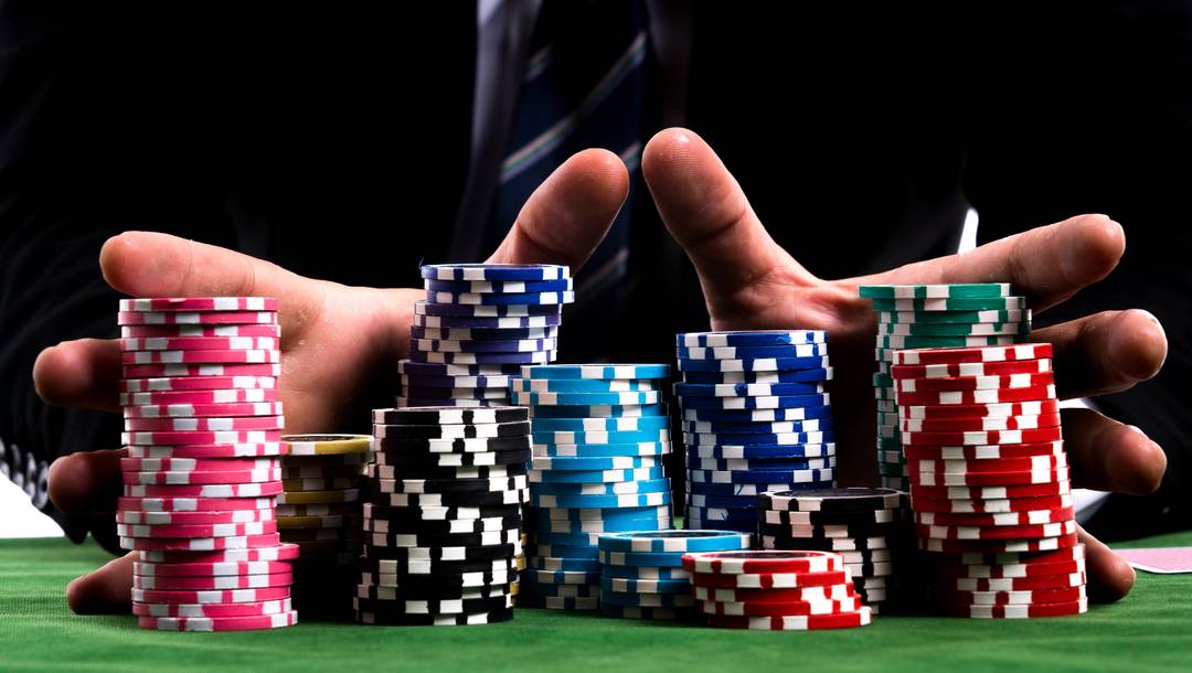 Hands pushing poker chips on a green poker table.