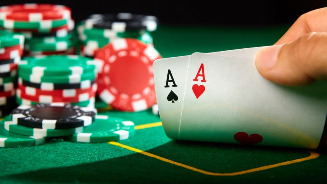 Poker player showing two aces on a green casino table.