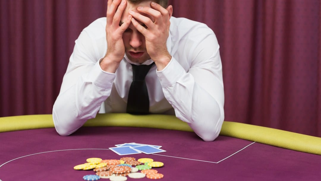 A man holds his head in his hands after a poker loss.