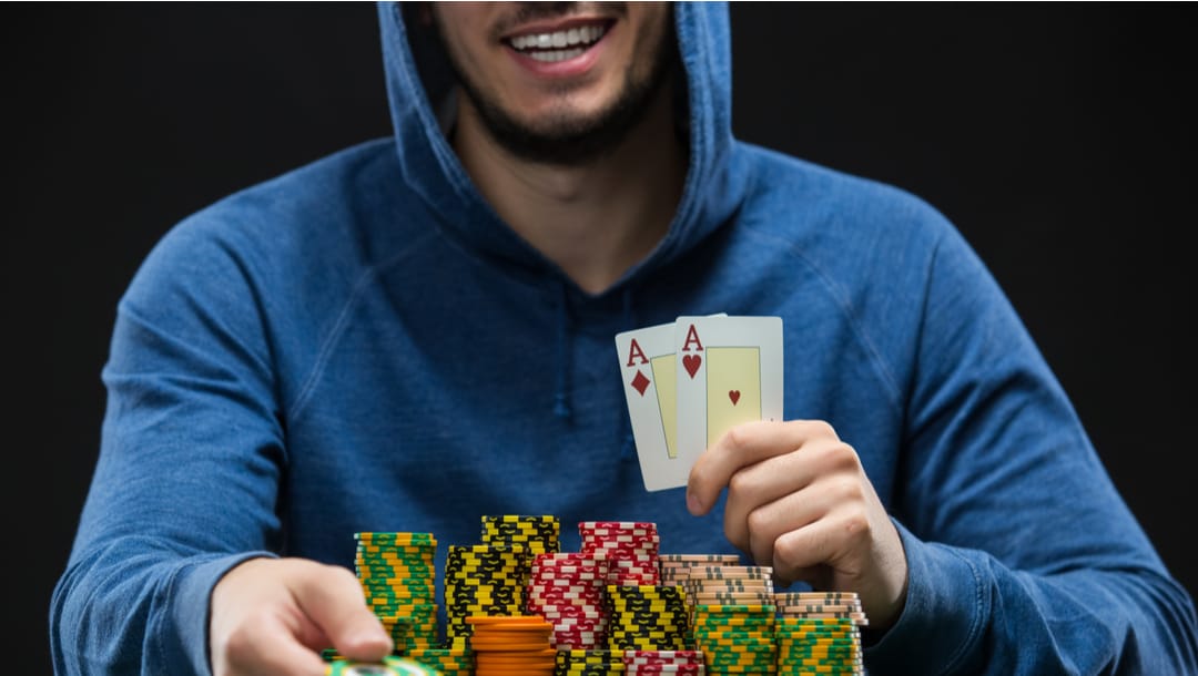 Smiling poker player shows double aces.