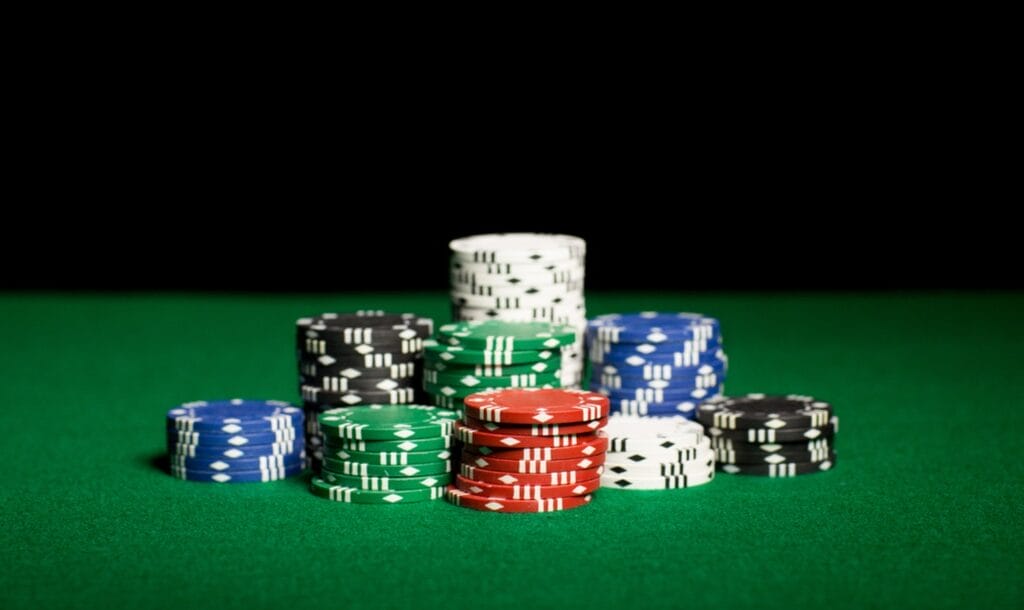 Stacks of various colored poker chips on a green felt casino table.
