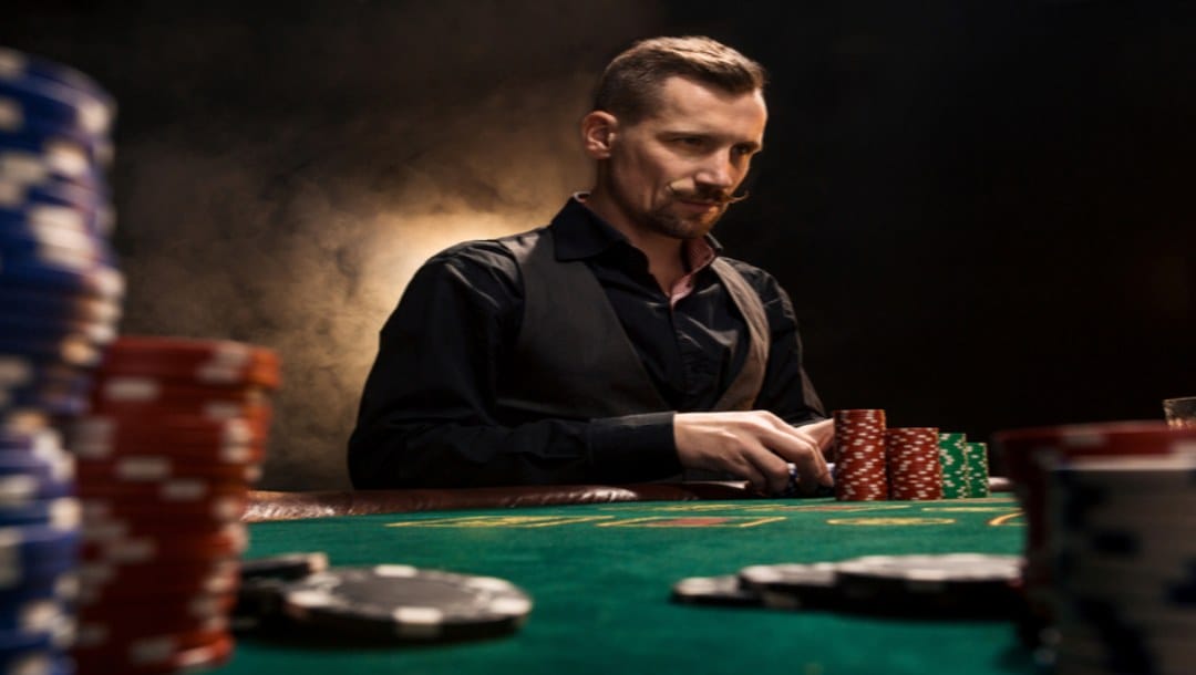 A man playing poker at a green felt poker table.