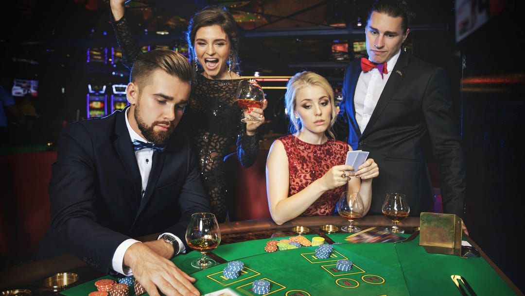 Four smartly dressed men and women at a poker table.