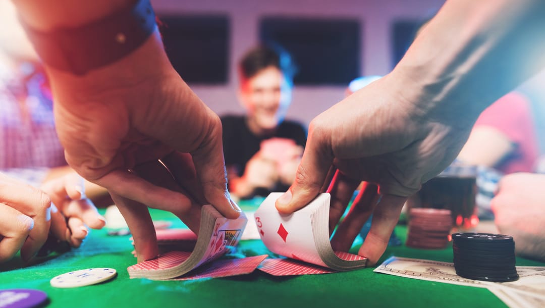 Close-up of a casino dealer shuffling cards at a poker table.