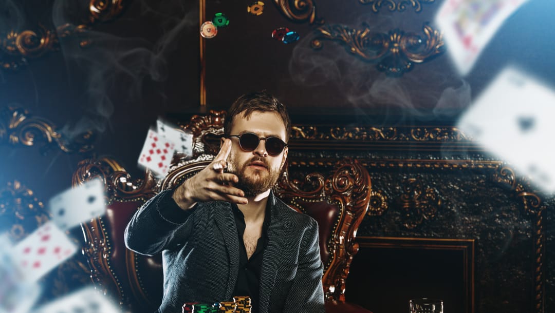 A smartly dressed man at a poker table surrounded by playing cards.