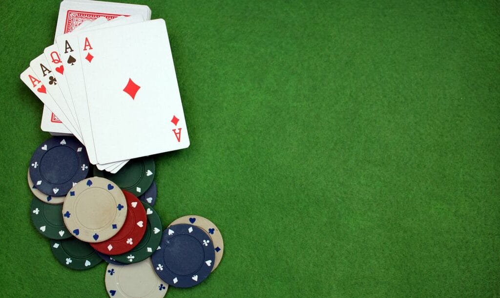 Cards and poker chips on a green felt poker table.