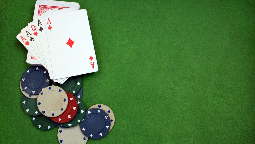 Cards and poker chips on a green felt poker table.