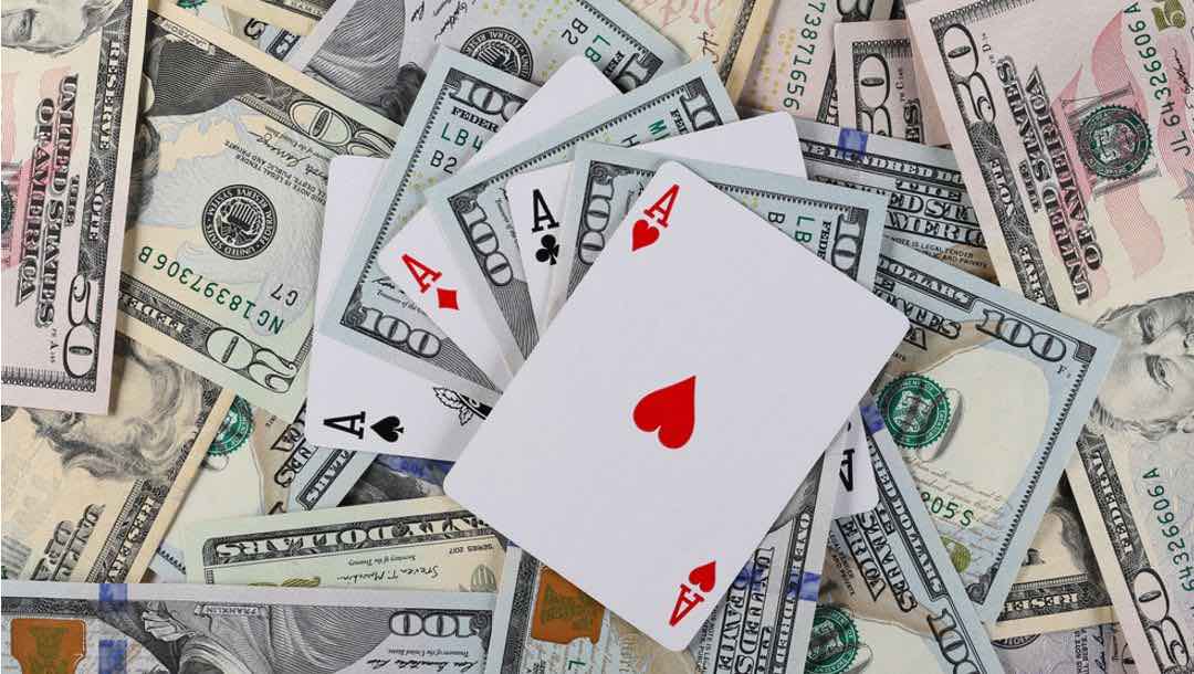 Playing cards mixed in amongst various denominations of dollar bills.