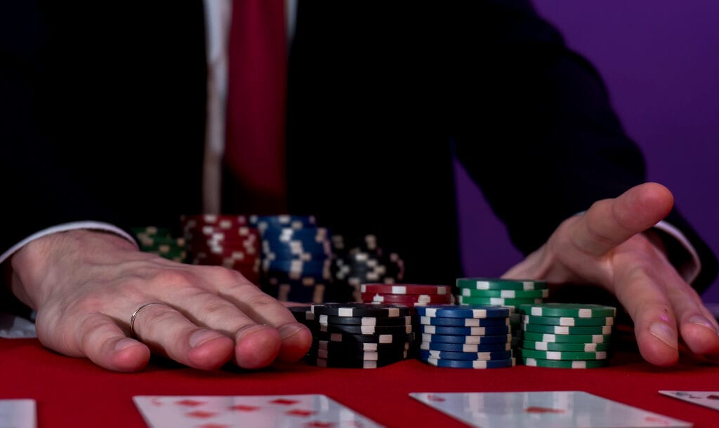 Man sitting at a poker table with chips and cards in front of him.
