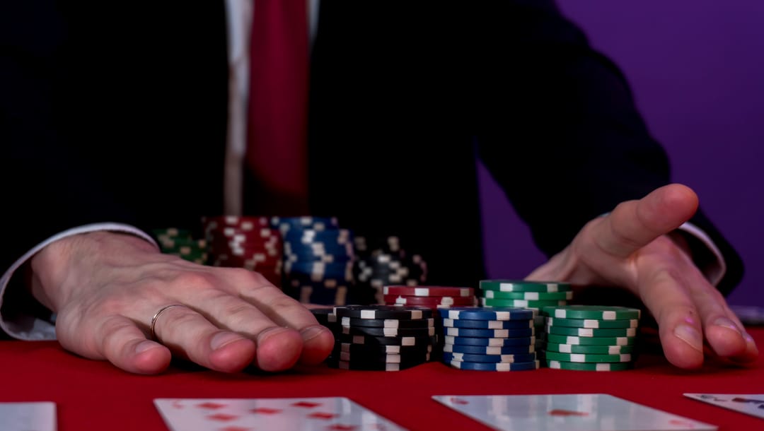 Man sitting at a poker table with chips and cards in front of him.